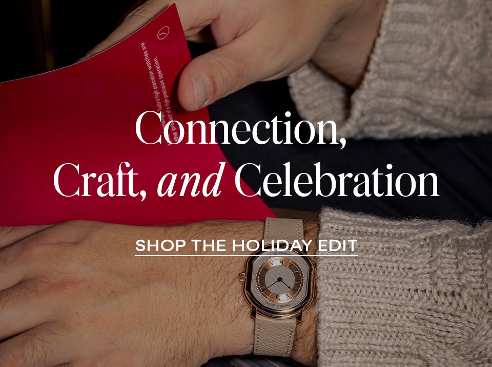 Man wearing a luxury watch and reading a red card, promoting The 1916 Company Holiday Watch Edit.