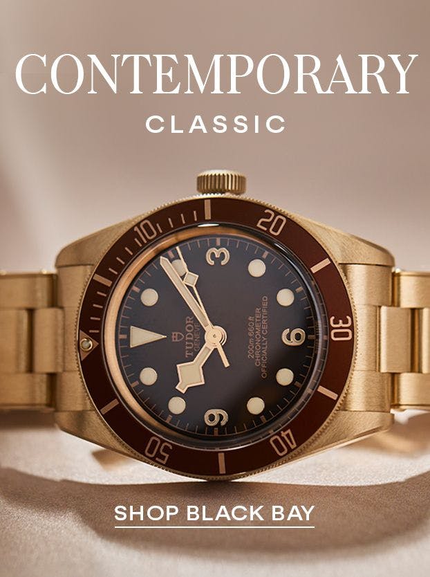 A close-up of a gold Tudor Black Bay watch with a black dial and a brown bezel, on a gold bracelet