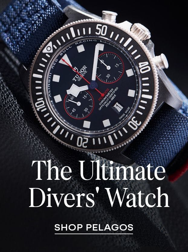 A close-up of a Tudor Pelagos chronograph watch with a blue dial, black bezel, and red accents, on a dark blue textile strap