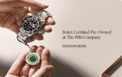 A person holds a Rolex Submariner watch with a black dial and silver bracelet, along with a green and white Rolex Certified Pre-Owned tag.