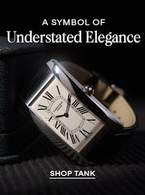 A close-up of a silver Cartier Tank watch with a white rectangular dial and Roman numerals, on a black leather strap