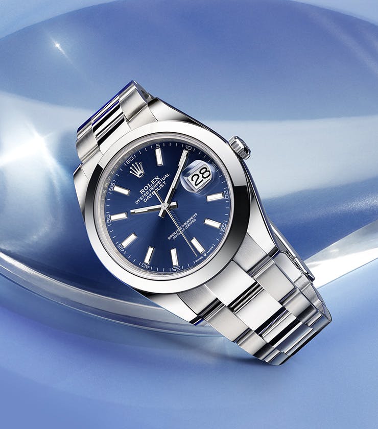 Rolex Datejust Blue Dial with smooth Bezel in front of blue background with glass object