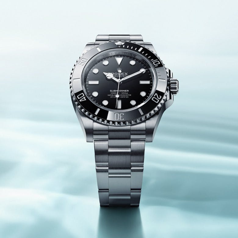 A Rolex Submariner watch with a black dial and silver bracelet, displayed against a light blue, watery background.